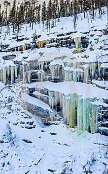 Vertical shot of trees and huge icicles hanging from rocks in Rovaniemi, Lapland, Finland