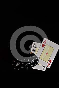 Vertical shot of two ace cards and poker chips under the lights on a black background