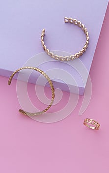 Vertical shot of two bracelets and ring on pink and purple background with copy space