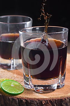 Vertical shot of two glasses of alcoholic drinks with soda and lime on the table