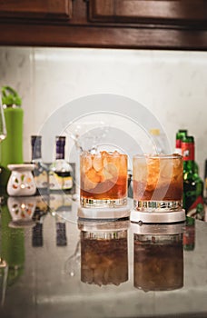 Vertical shot of two glasses with exotic orange cocktails in them on the counter at a bar