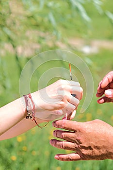 Vertical shot of two pairs of hands holding a fishing float with a fishing line in nature