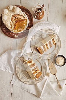 Vertical shot of two plates and a wooden tray with slices of a white coconut flake cake