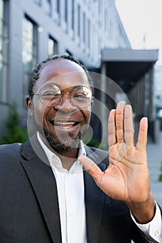 Vertical shot, video call of successful businessman boss, African American man outside office building looking into