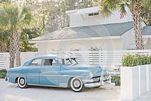 Vertical shot of a vintage blue car parked in front of a home