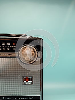 Vertical shot of a vintage transistor radio against a turquoise wall