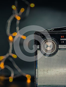 Vertical shot of a vintage transistor radio with glowing lights in the background