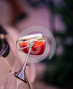 Vertical shot of a vintage vehicle's side mirror reflecting the light