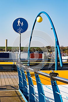 Vertical shot of a walkway over a metro overground tube in Prague with symbols against the blue sky