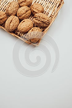 Vertical shot of walnuts on wicker basket isolated on a white background