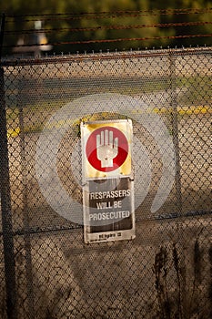 Vertical shot of the warning sign on the metal fence. Trespassers will be prosecuted.