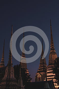 Vertical shot of Wat pho old Buddhist temples in Thailand against a dark sky at night