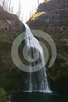 Vertical shot of a waterfall flowing to the river from the middle of an enormous rock
