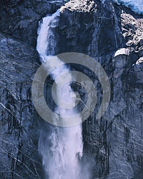 Vertical shot of a waterfall gushing down a stone wall