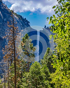 Vertical shot of a waterfall in the mountains under the beautiful cloudy sky in the background