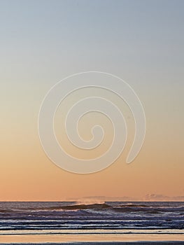 Vertical shot of the waves of Pacific Ocean during sunset in Oregon