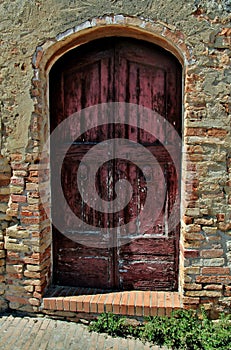 Vertical shot of a weathered door with a brick wall