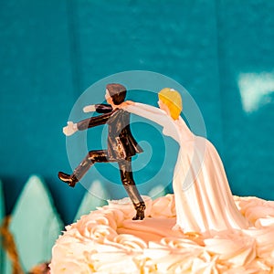 Vertical shot of a wedding cake topper of the groom running away