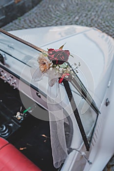 Vertical shot of wedding roses on a white car parked in the street