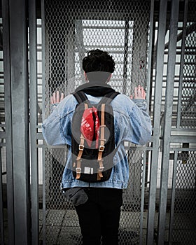 Vertical shot of a white caucasian male from the back with hands on the netted door