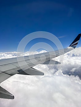 Vertical shot of the white clouds and blue sky captured from a plane