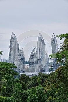 Vertical shot of white glassy buildings of Singapore surrounded by green nature under the calm sky