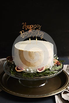 Vertical shot of a white happy birthday dream cake with green leaves at the bottom