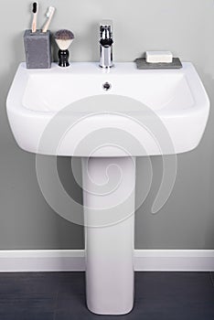 Vertical shot of a white modern pedestal bathroom sink with soap and toothbrushes