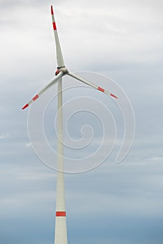 Vertical shot of a wind turbine on a cloudy sky background