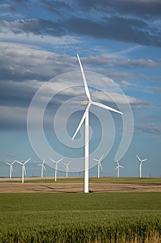 Vertical shot of Wind Turbine Towers under the cloudy blue sky in the countryside of Oregon