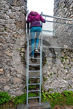 Vertical shot of a woman climbing the stairs on The Cachtice Castle, Slovakia