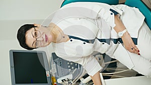 Vertical shot of a woman doctor of ultrasound diagnostics near the machine.