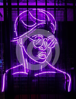 Vertical shot of a woman with eyeglass formed from violet lights