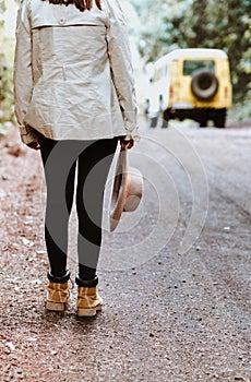 Vertical shot of a woman standing on the side of the road holding her hat with a blurry background