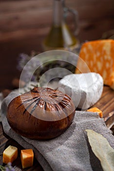 Vertical shot of a wooden board with Neuchatel and Colby orange cheese served with bread and herbs