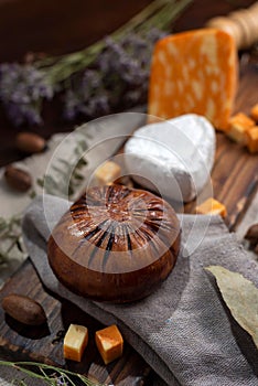 Vertical shot of a wooden board with Neuchatel and Colby orange cheese served with bread and herbs