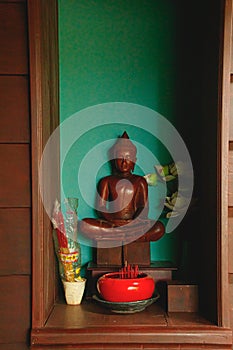 Vertical shot of a wooden Buddha statue in lotus meditation position