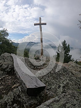 Vertical shot of a wooden cross on a hill under a cloudy sky