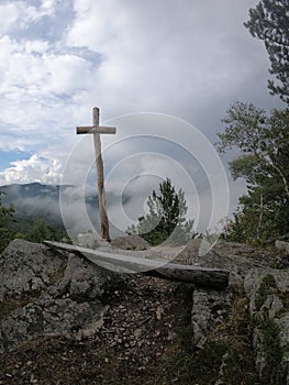 Vertical shot of a wooden cross on a hill under a cloudy sky