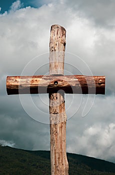 Vertical shot of a wooden cross under a cloudy sky