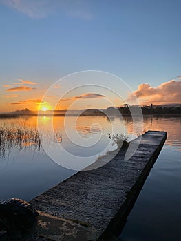 Vertical shot of a wooden pier on a tranquil lake at sunset