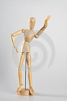 Vertical shot of a wooden pose doll with one hand in the air on a white background