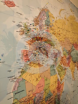 Vertical shot of a world map on a wall with colorful pins attached on the Europe continent