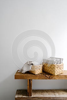 Vertical shot of woven baskets with clean towels on wooden bench in bathroom