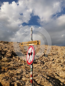Vertical shot of "Life on mars trial" with "no dogs" signages against rocky cliff in Pag Island photo