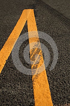 Vertical shot of yellow marking lines on an asphalt road
