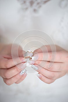 Vertical shot of young Caucasian bride holding a diamond wedding band and an engagement ring with both hands