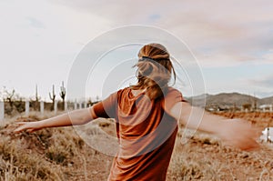 Vertical shot of a young, cute blond woman posing in a beautiful, way with her arms open