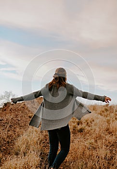 Vertical shot of a young, cute blond woman posing in a beautiful, way with her arms open