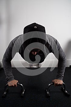 Vertical shot of a young fit male exercising on push-up grips